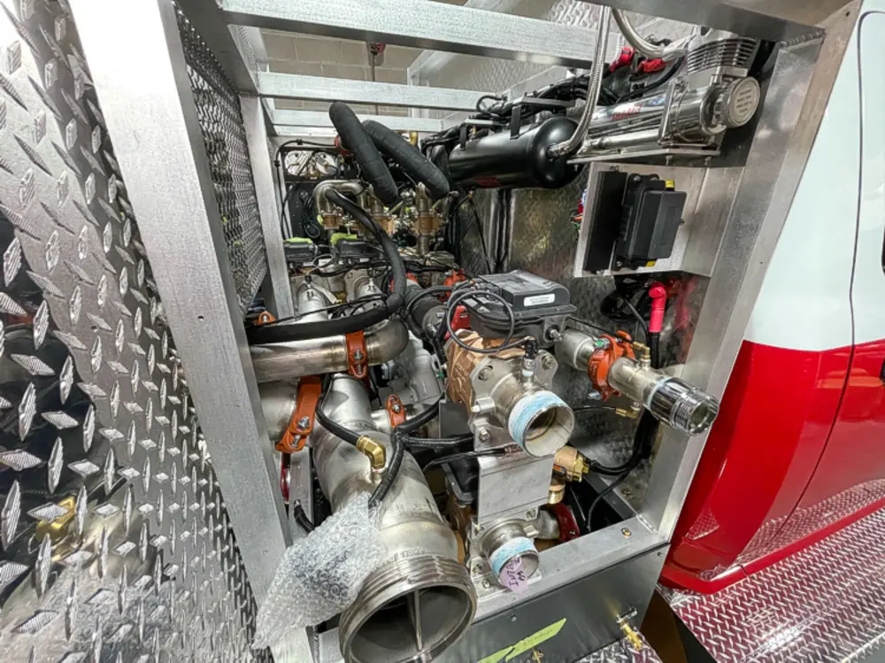 Exterior view of small fire truck showing cab, body compartments, and wheel/tire area.